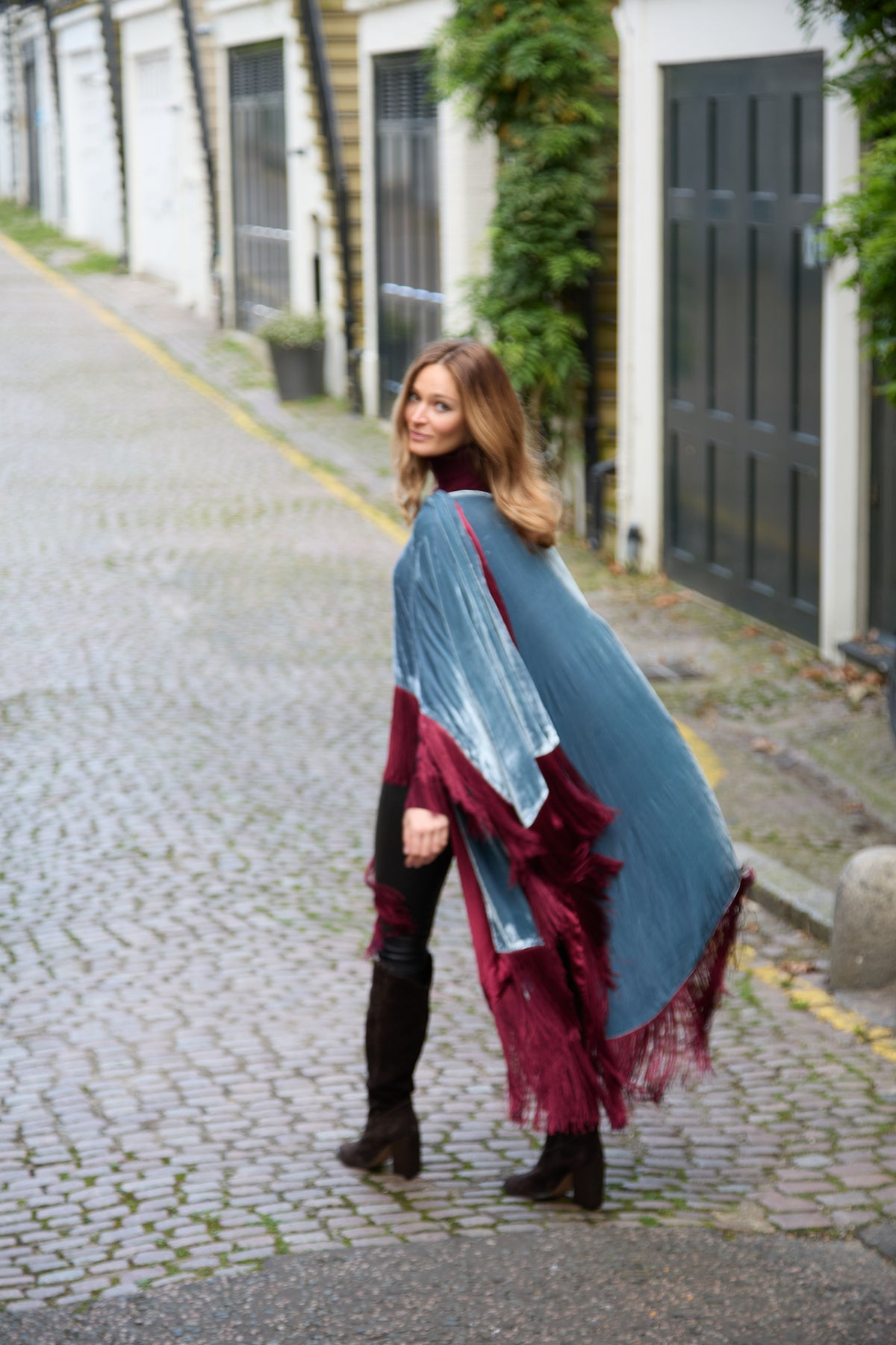 The Summer Cloud Poncho in pale blue silk velvet with burgundy fringe, in motion, London mews