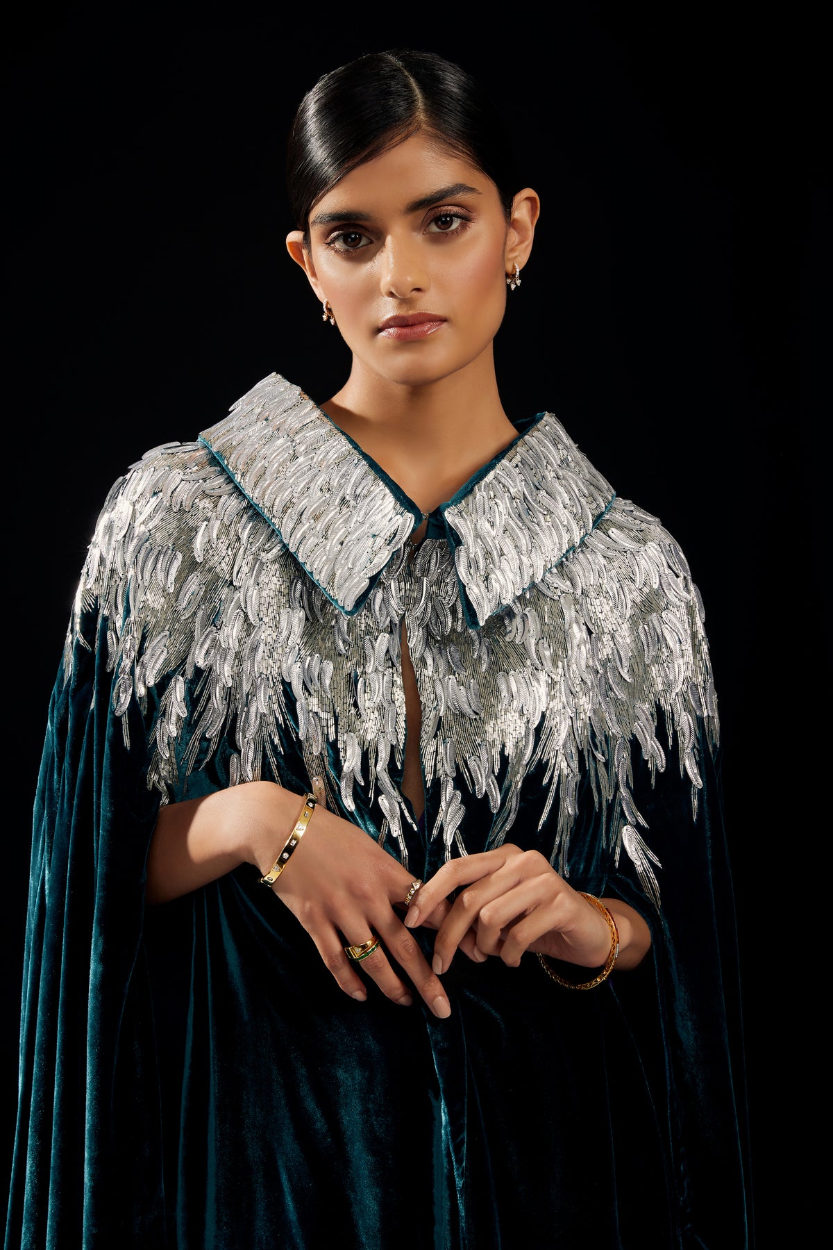 The Silver Feather Cape in petrol silk velvet with silver beaded feathers, front view, dark studio