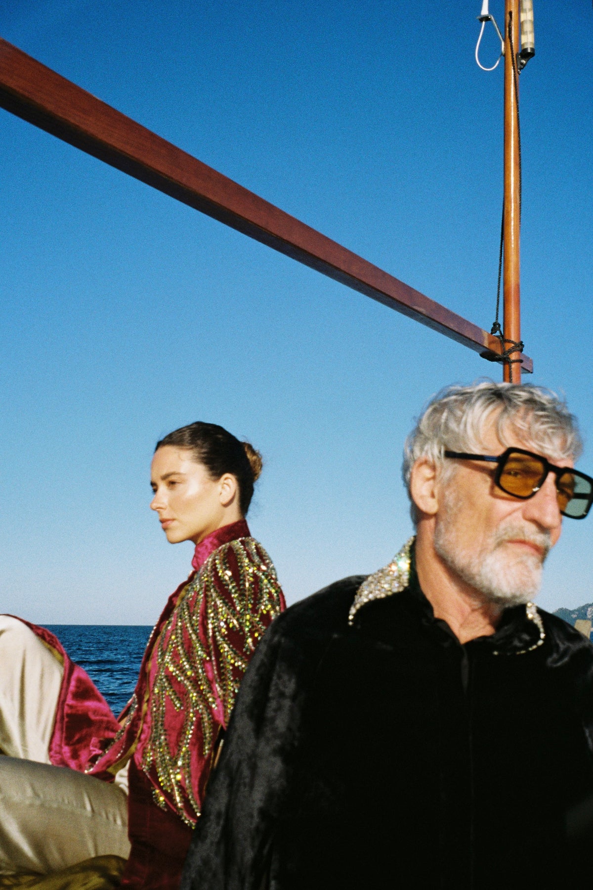 The Golden Collar Cape in black silk velvet with golden sequin collar, with the Royal Garden Cape, on a boat at sea