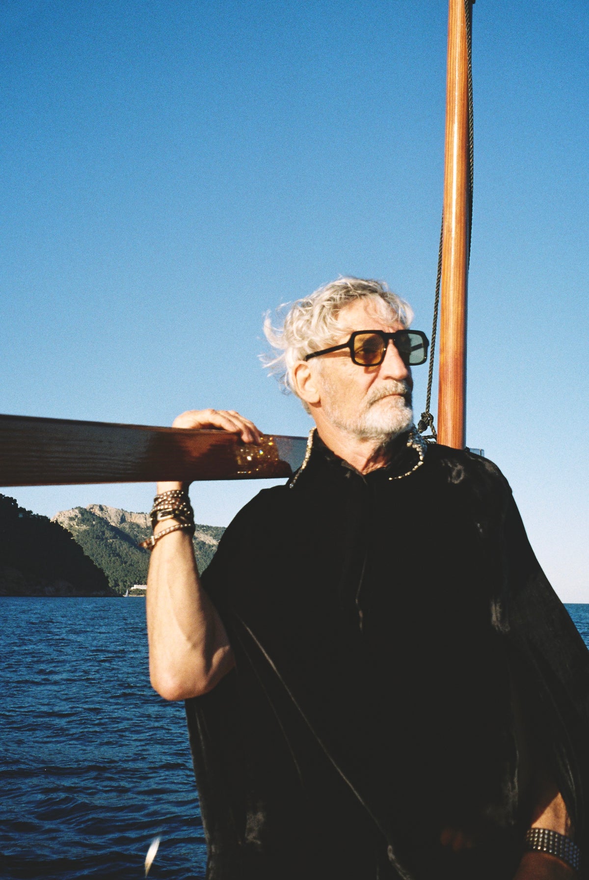 The Golden Collar Cape in black silk velvet with golden sequin collar, on a sailing boat at sea