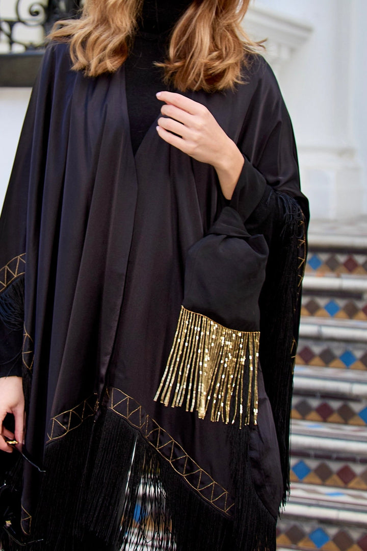 The Black Beaded Gold Knot Bag in black with gold beaded fringe, carried with the Nomad Poncho, London townhouse steps