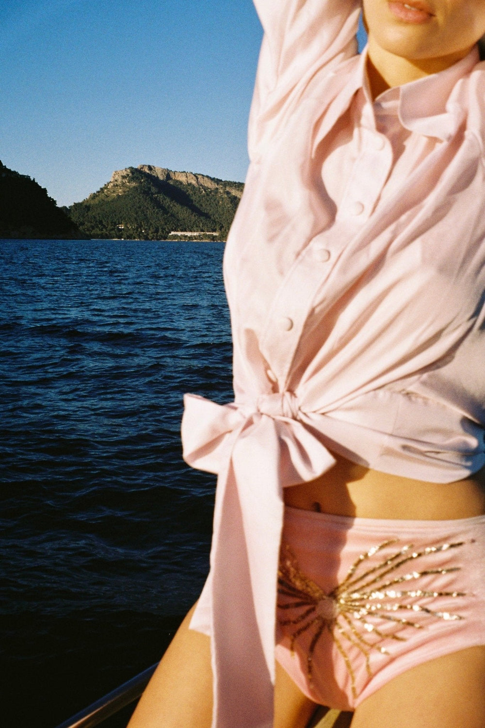 The Bow Blouse in pale pink silk twill, bow detail, on a boat