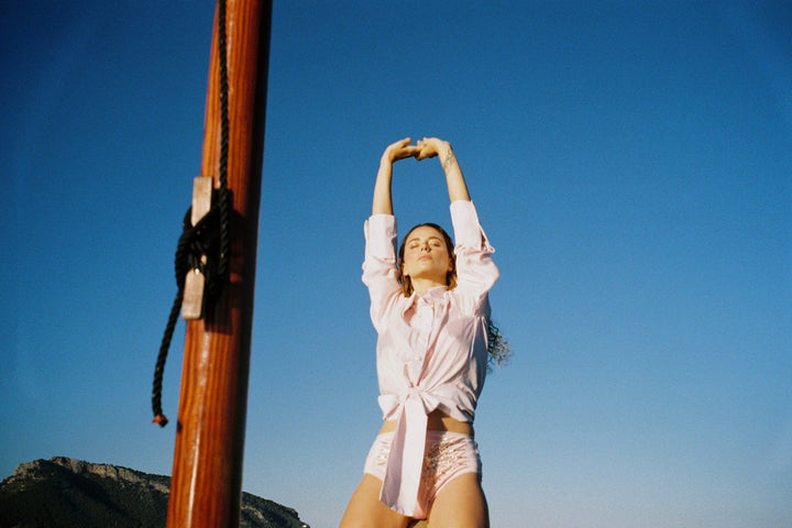 The Bow Blouse in pale pink silk twill, on a sailing boat at sea