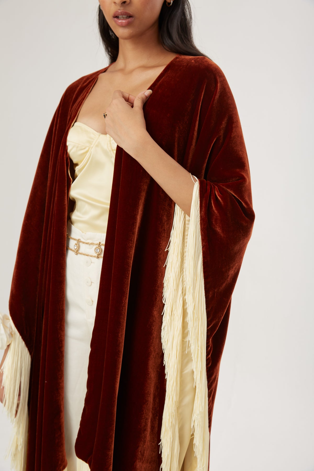 The Bronze Poncho in bronze silk velvet with cream fringe, close-up, studio