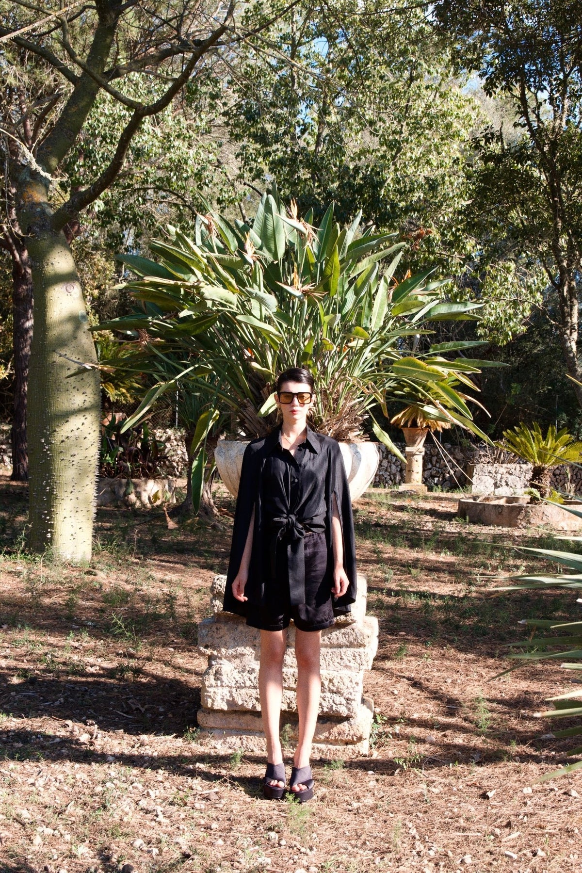 The Cape Sleeve Blouse in black silk twill, front view, garden