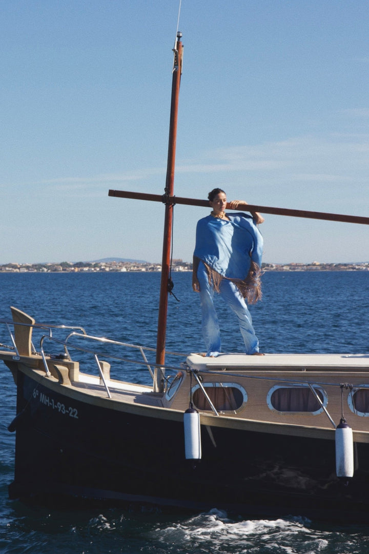 The Cornflower Trousers in powder blue silk, on a sailing boat at sea