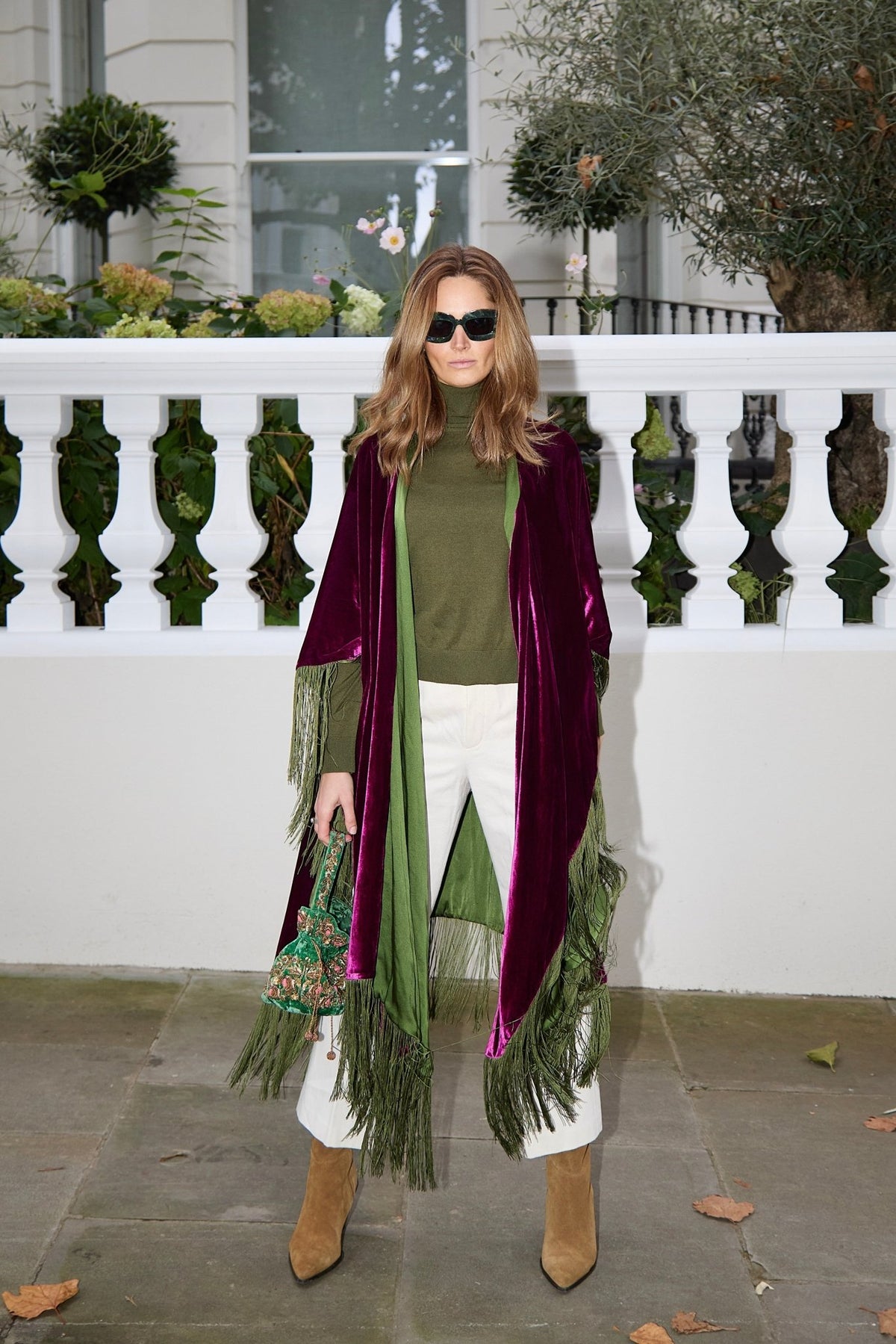 The Dahlia Poncho in magenta silk velvet with olive green fringe, front view, London terrace