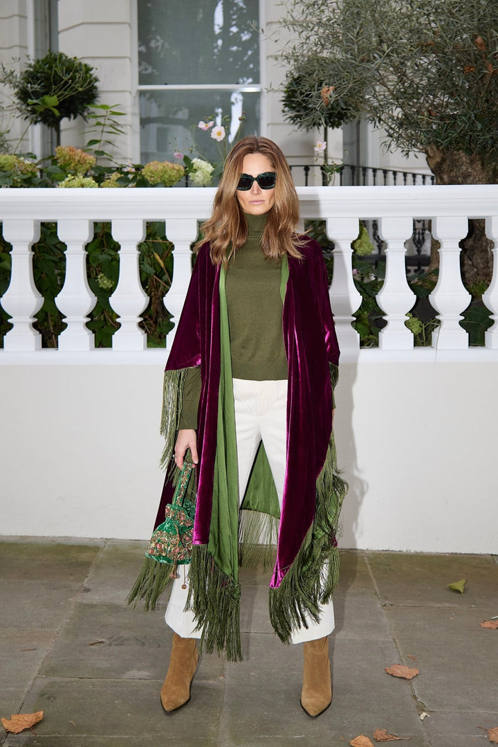 The Dahlia Poncho in magenta silk velvet with olive green fringe, front view, London terrace