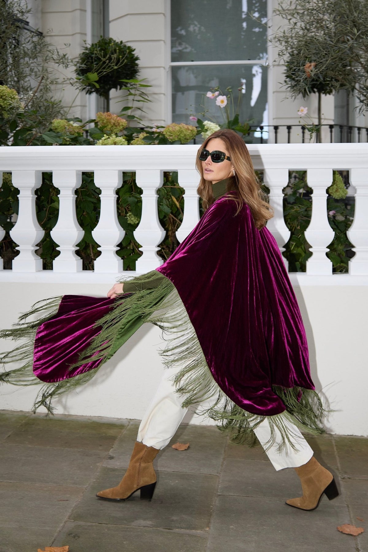 The Dahlia Poncho in magenta silk velvet with olive green fringe, in motion, London terrace