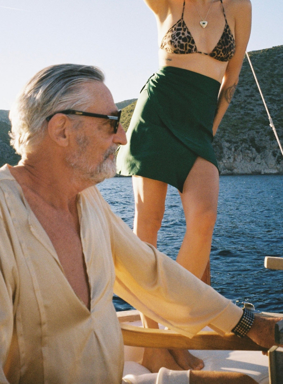 The Emerald Wrap Skirt in emerald green silk, close-up, on a boat