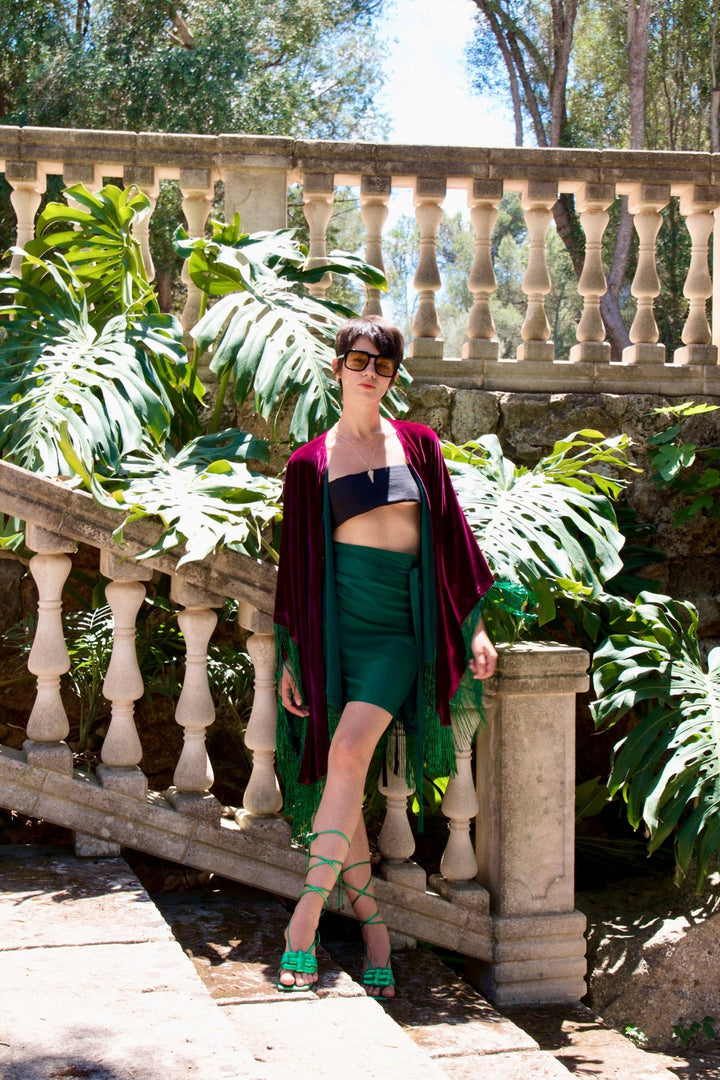The Emerald Wrap Skirt in emerald green silk, front view, stone staircase