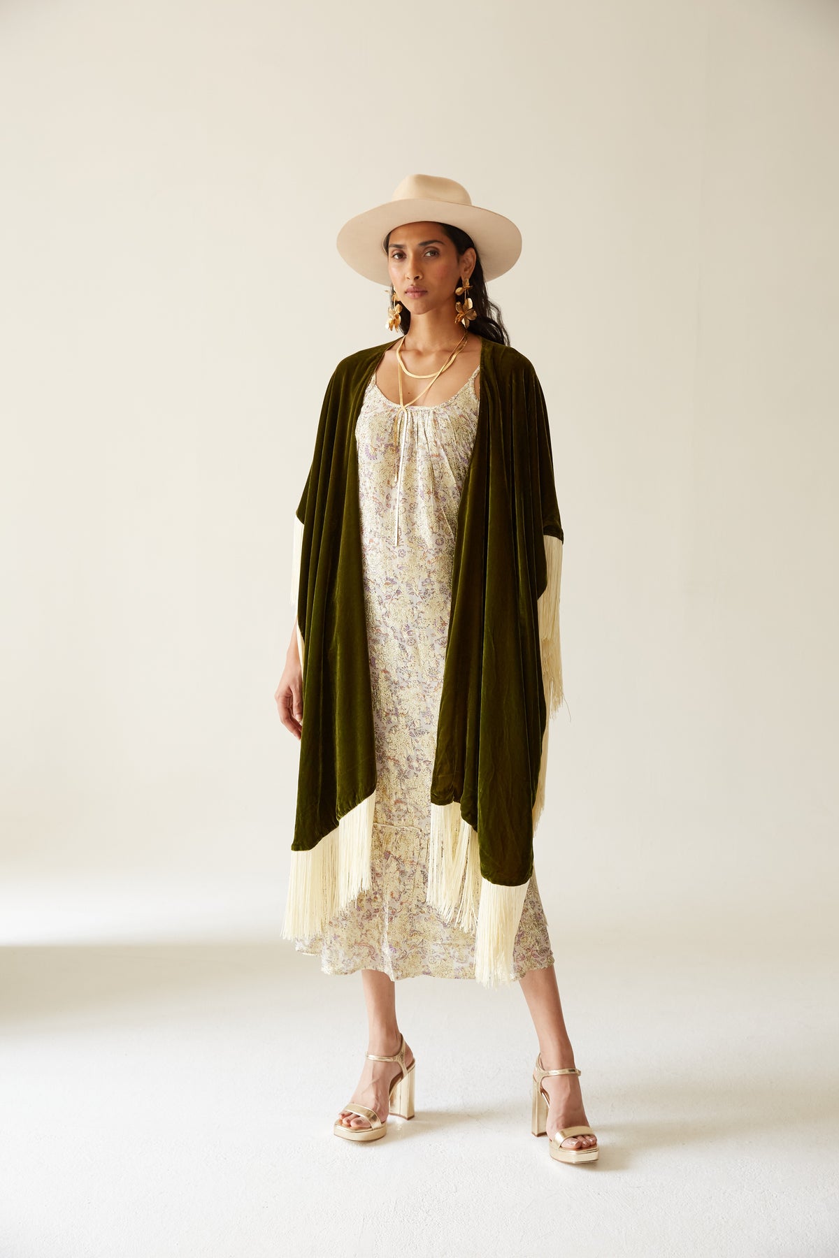 The Evergreen Poncho in olive green silk velvet with cream fringe, full length, studio