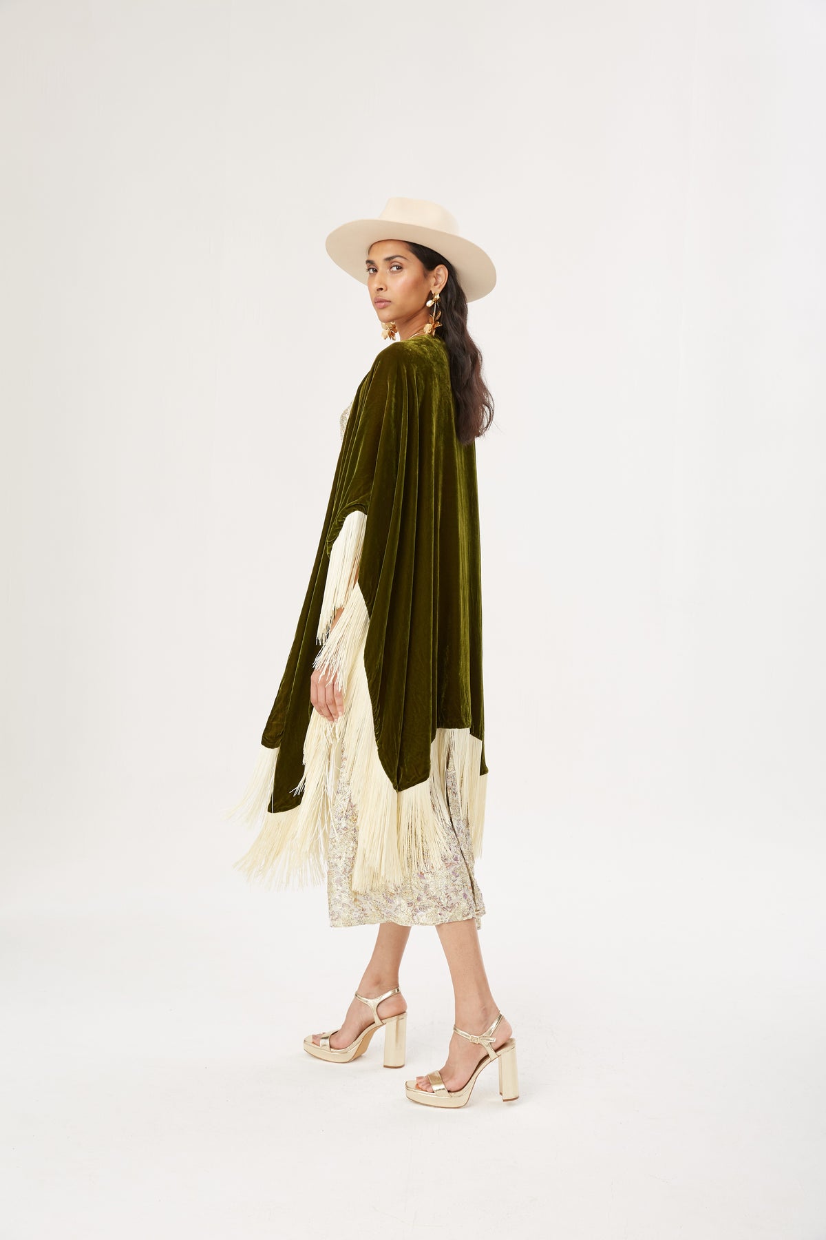 The Evergreen Poncho in olive green silk velvet with cream fringe, full length, studio