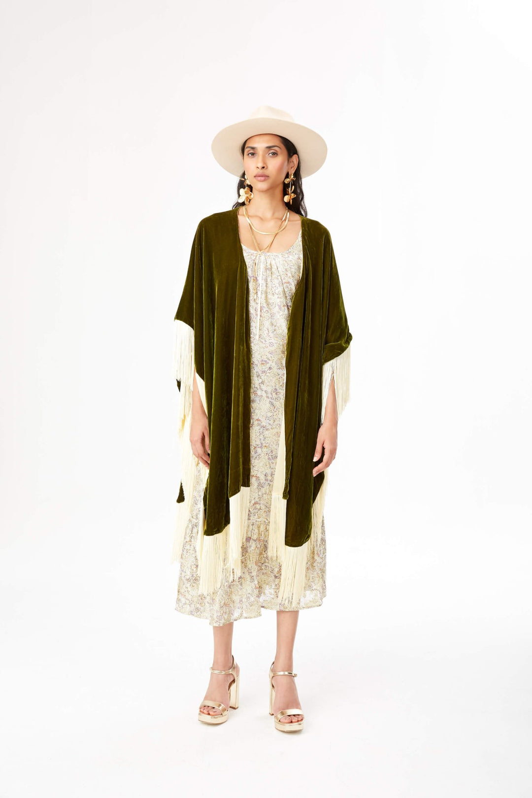 The Evergreen Poncho in olive green silk velvet with cream fringe, front view, studio