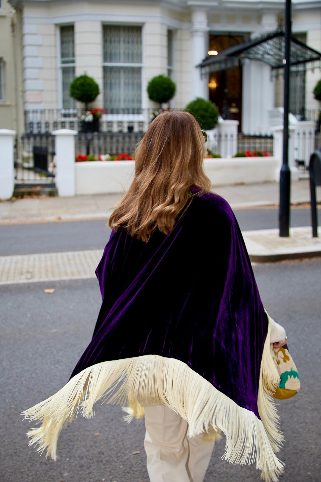 The Gatsby Poncho in purple silk velvet with champagne fringe, back view, London street
