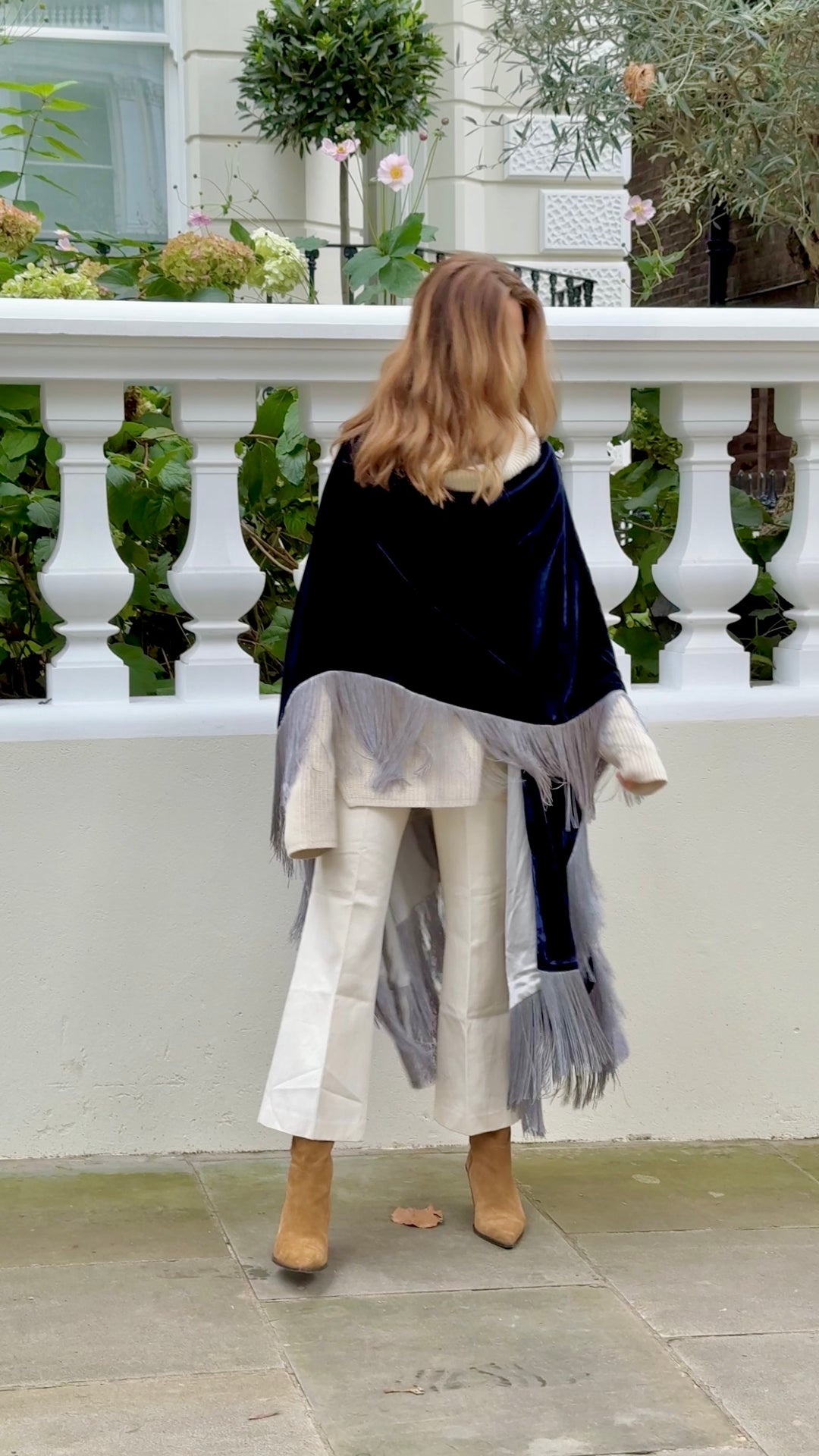 The Glory of the Snow Poncho in midnight blue silk velvet with silver fringe, back view, white balustrade terrace