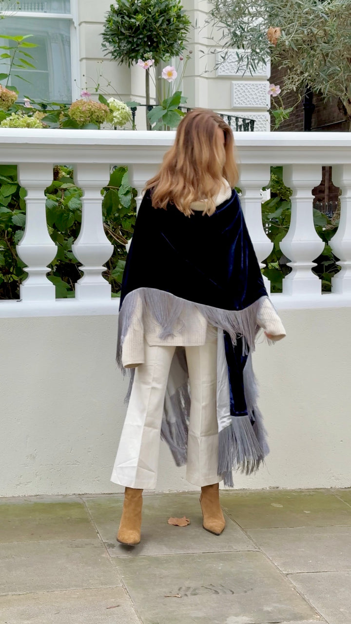 The Glory of the Snow Poncho in midnight blue silk velvet with silver fringe, back view, white balustrade terrace