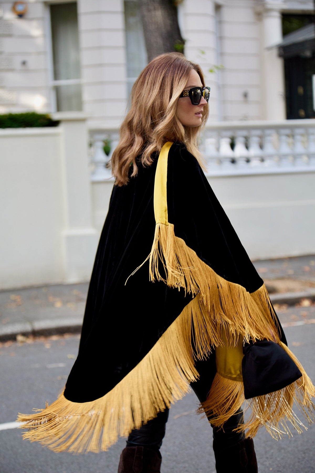 The Golden Age Poncho from behind, gold fringe swinging, London street