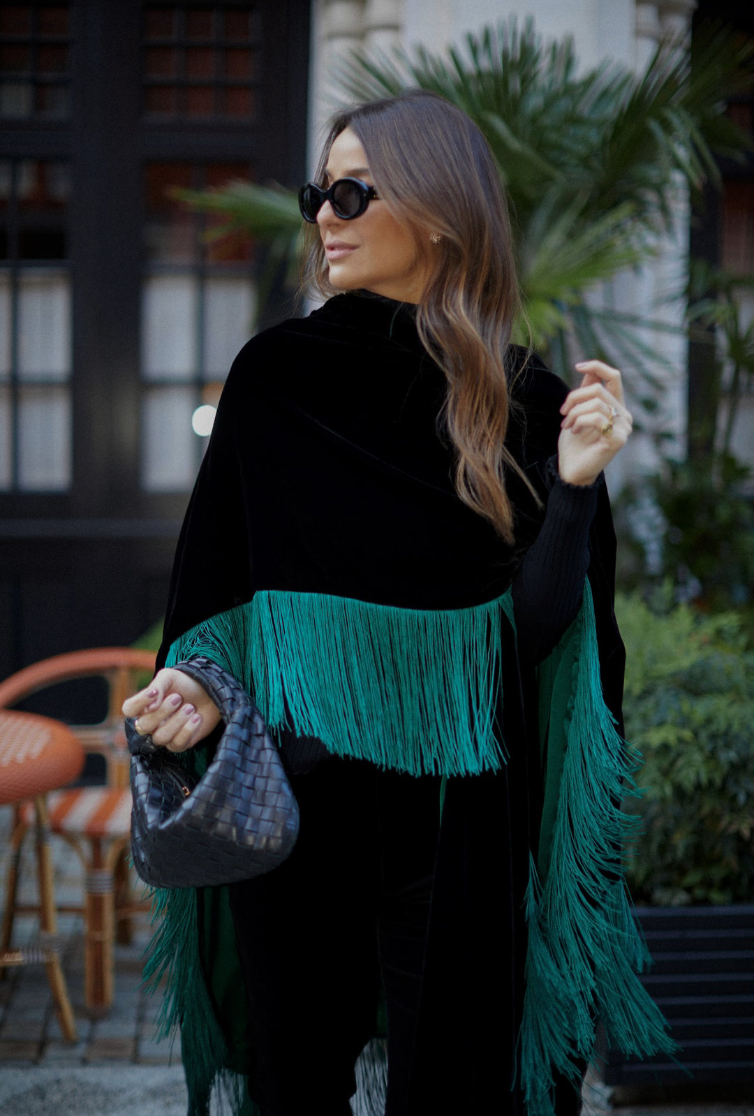 The Gypset Poncho in black silk velvet with emerald fringe, front detail, London street