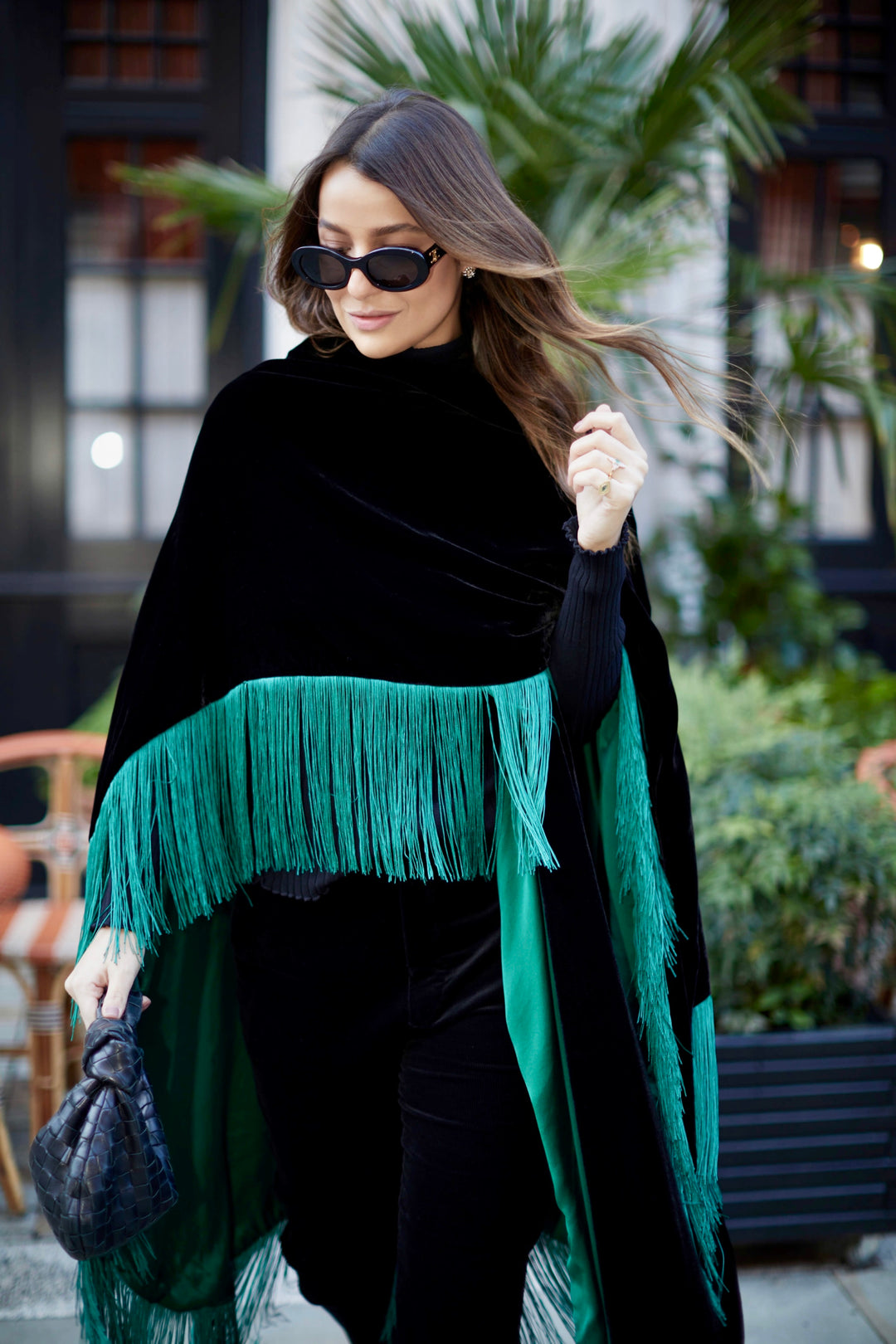 The Gypset Poncho in black silk velvet with emerald fringe, front view, London street