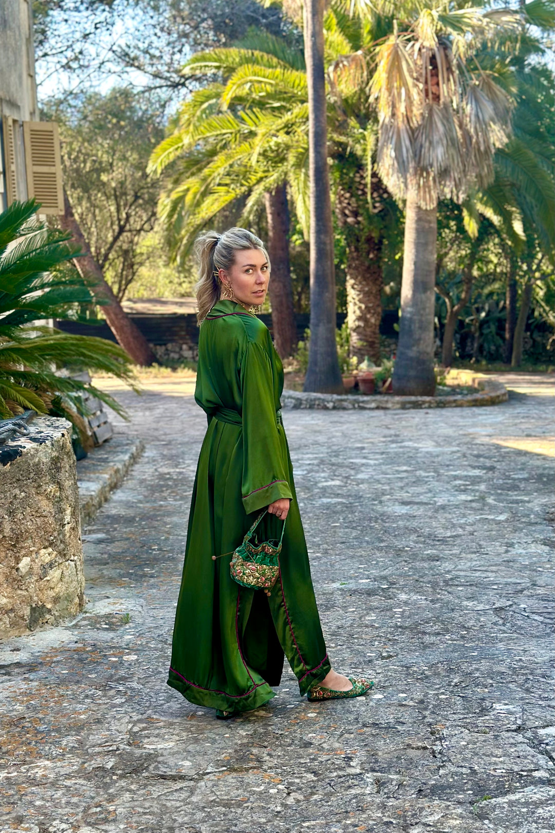 The Jade Vine Kimono in emerald green heavy silk, side view, garden courtyard