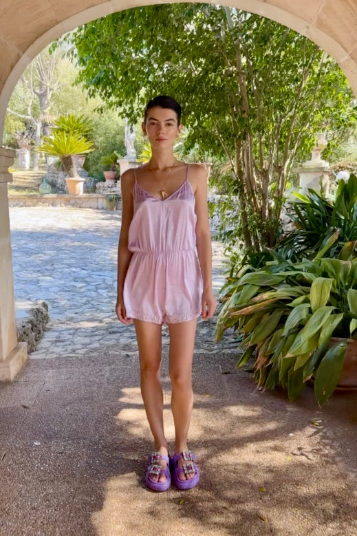 The Lavender Playsuit in lavender silk, front view, garden archway
