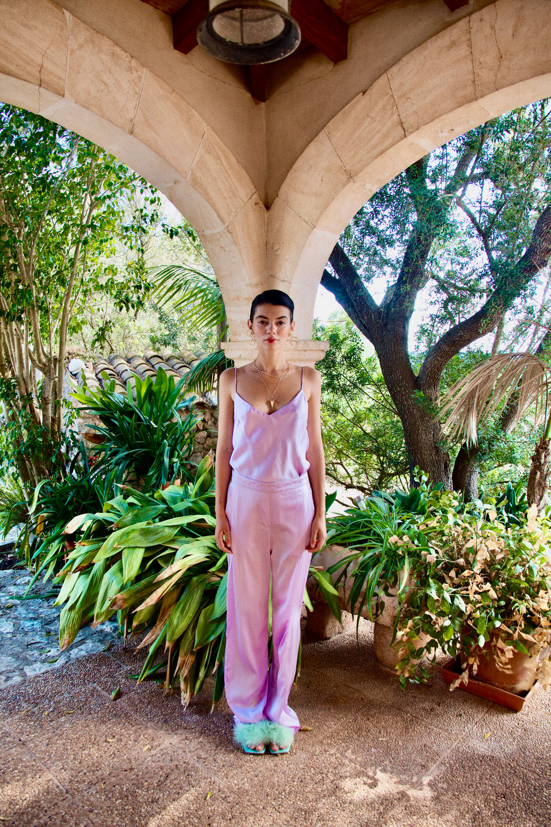 The Lavender Poncho's matching camisole and trousers in lavender silk, front view, garden archway