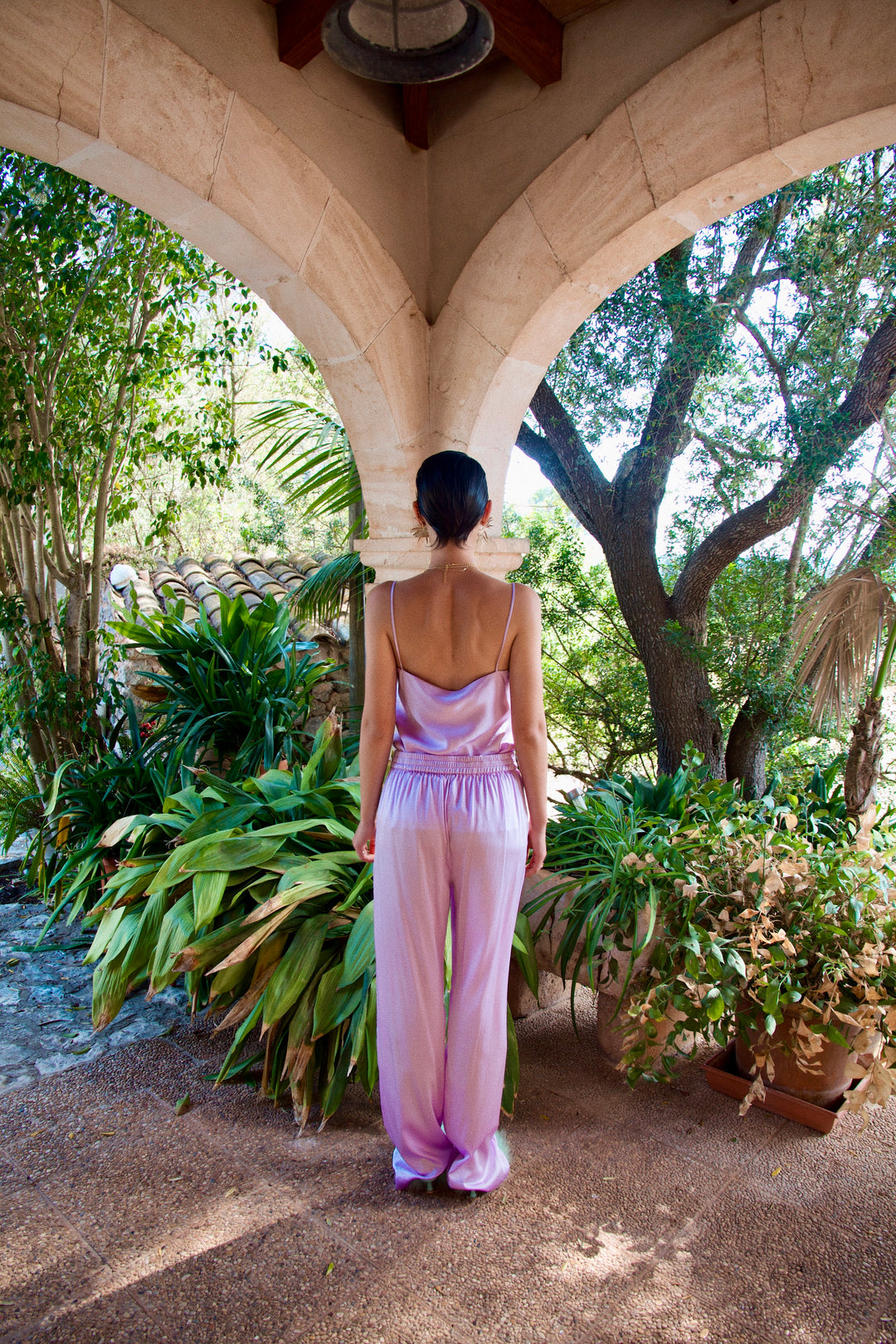The Lavender Poncho's matching camisole and trousers in lavender silk, back view, garden archway