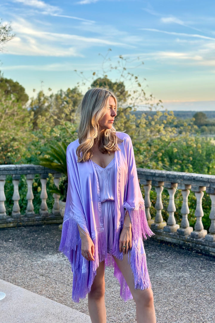 The Lavender Poncho in lavender silk with fringed hem, worn with the Lavender Playsuit, terrace at sunset