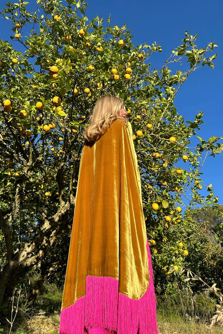 The Limoncello Poncho in golden yellow silk velvet with pink fringe, back view, lemon grove