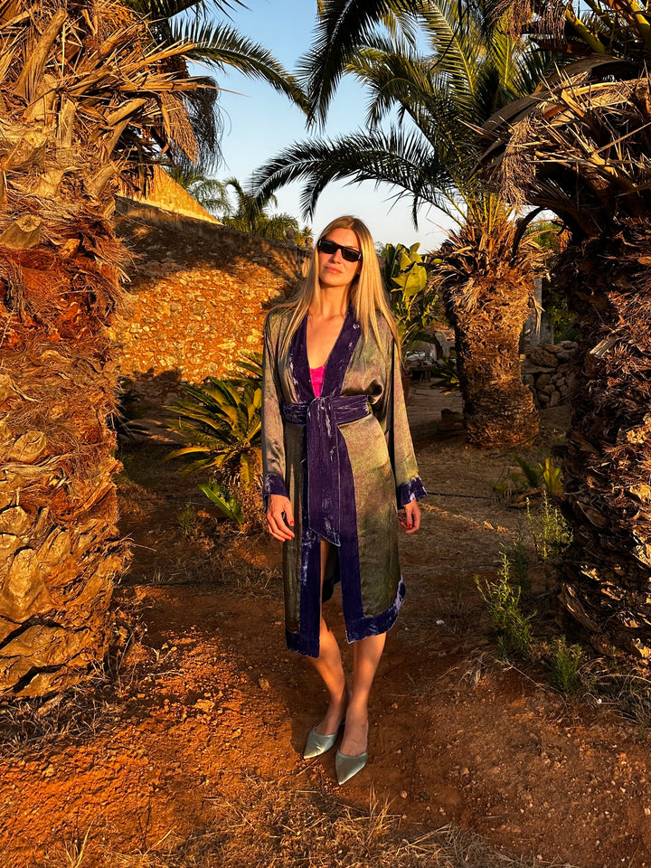 The Mazestroom Kimono, Purple and Green, in iridescent green and purple maze-print silk with velvet trim, front view, palm garden