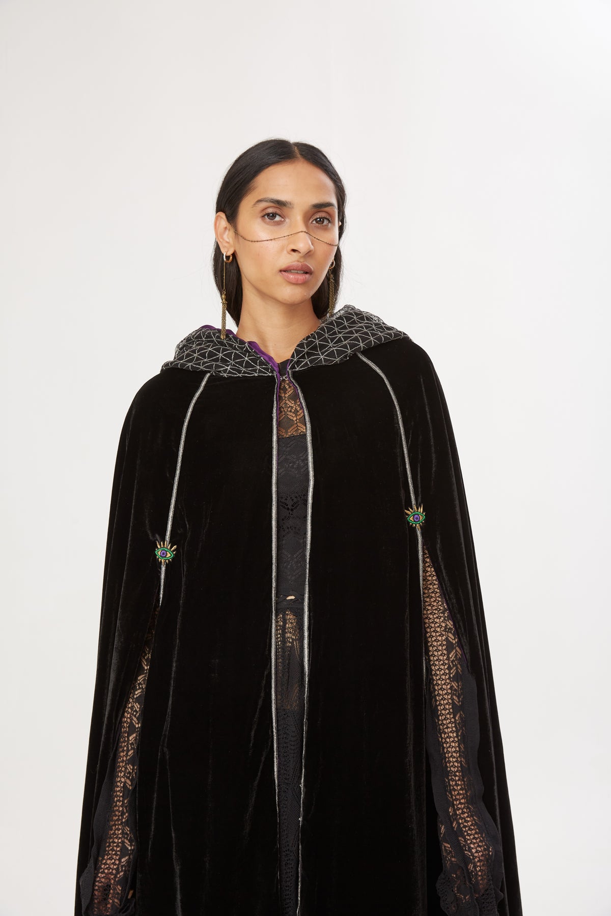 The Mystery Cape in black silk velvet with purple lining and embroidered hood, close-up, studio