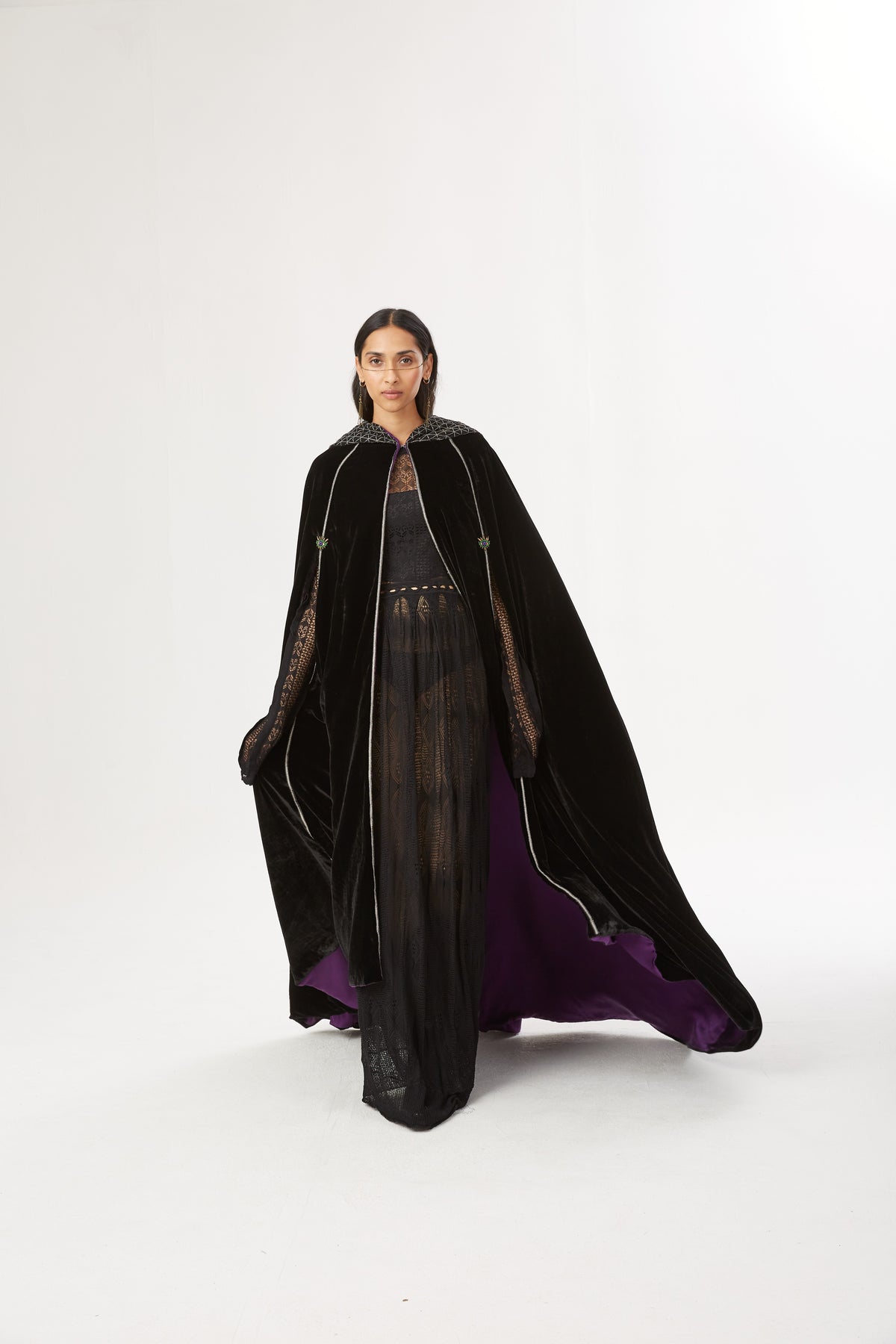 The Mystery Cape in black silk velvet with purple lining and embroidered hood, walking, studio