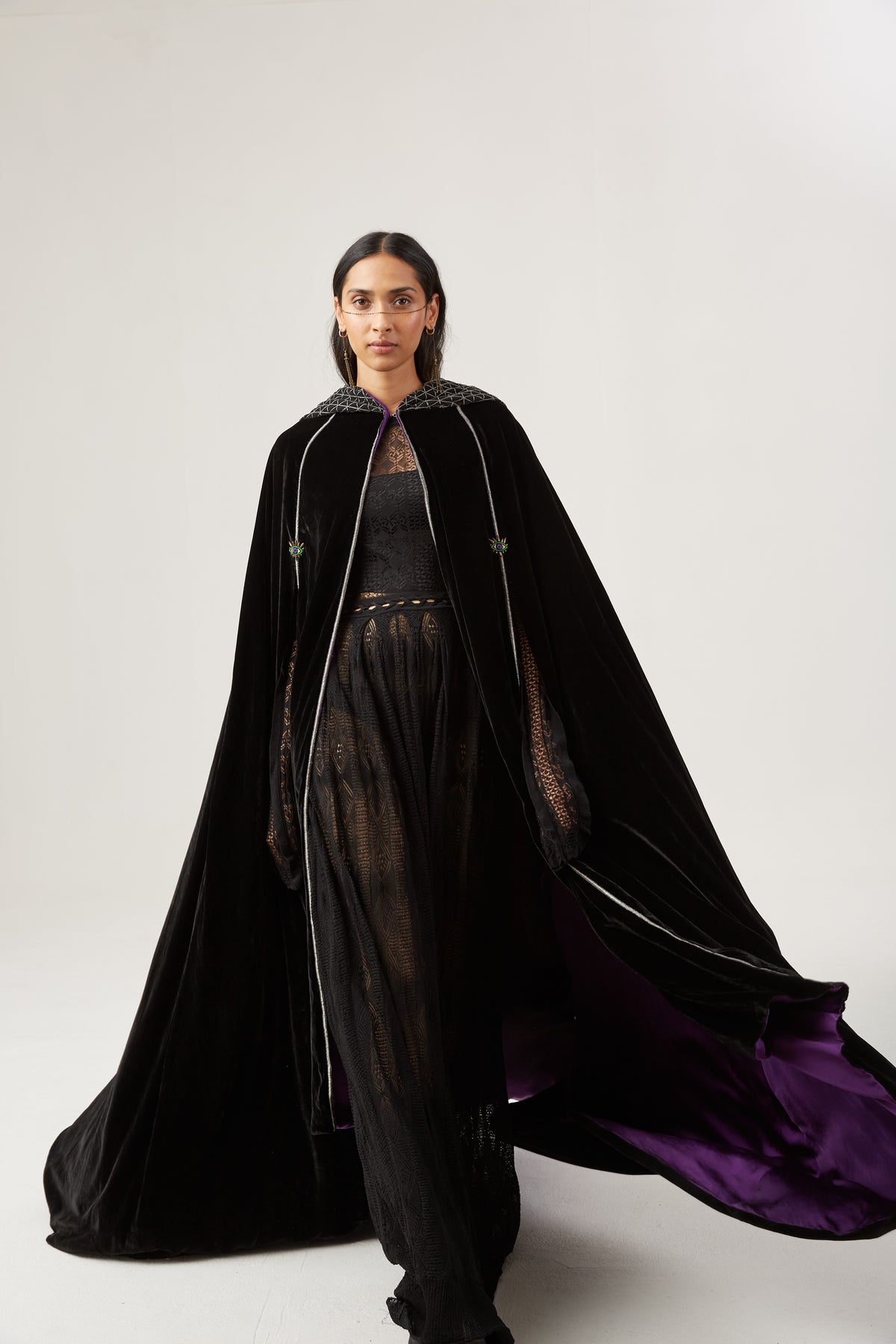 The Mystery Cape in black silk velvet with purple lining and embroidered hood, in motion, studio