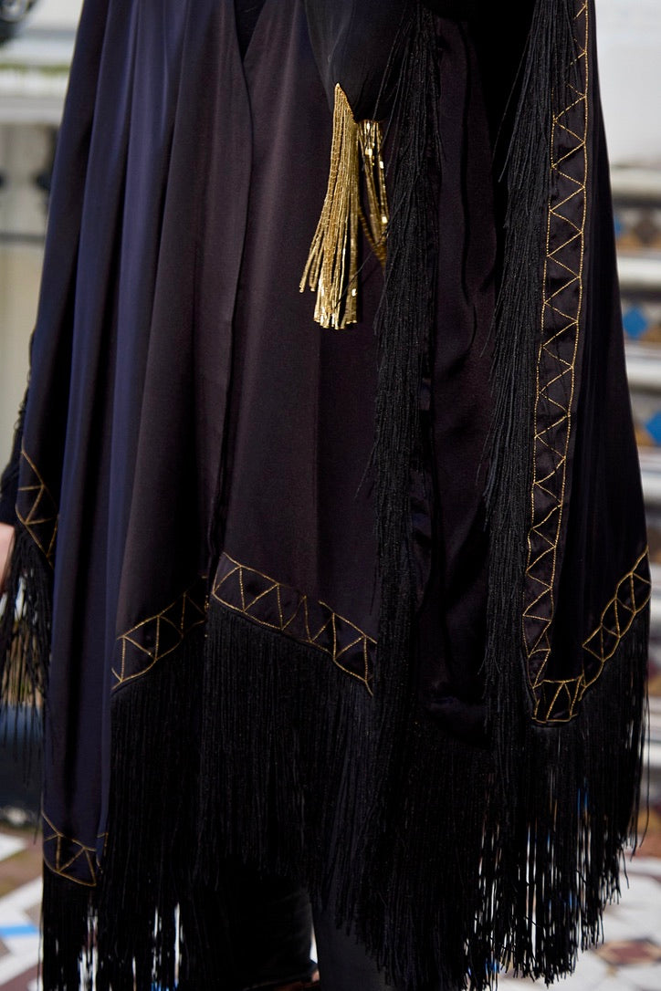 The Nomad Poncho in black silk with gold hand embroidery and black fringe, embroidery and fringe detail