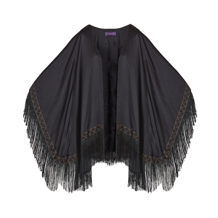 The Nomad Poncho in black silk with gold hand embroidery and black fringe, flat lay, studio