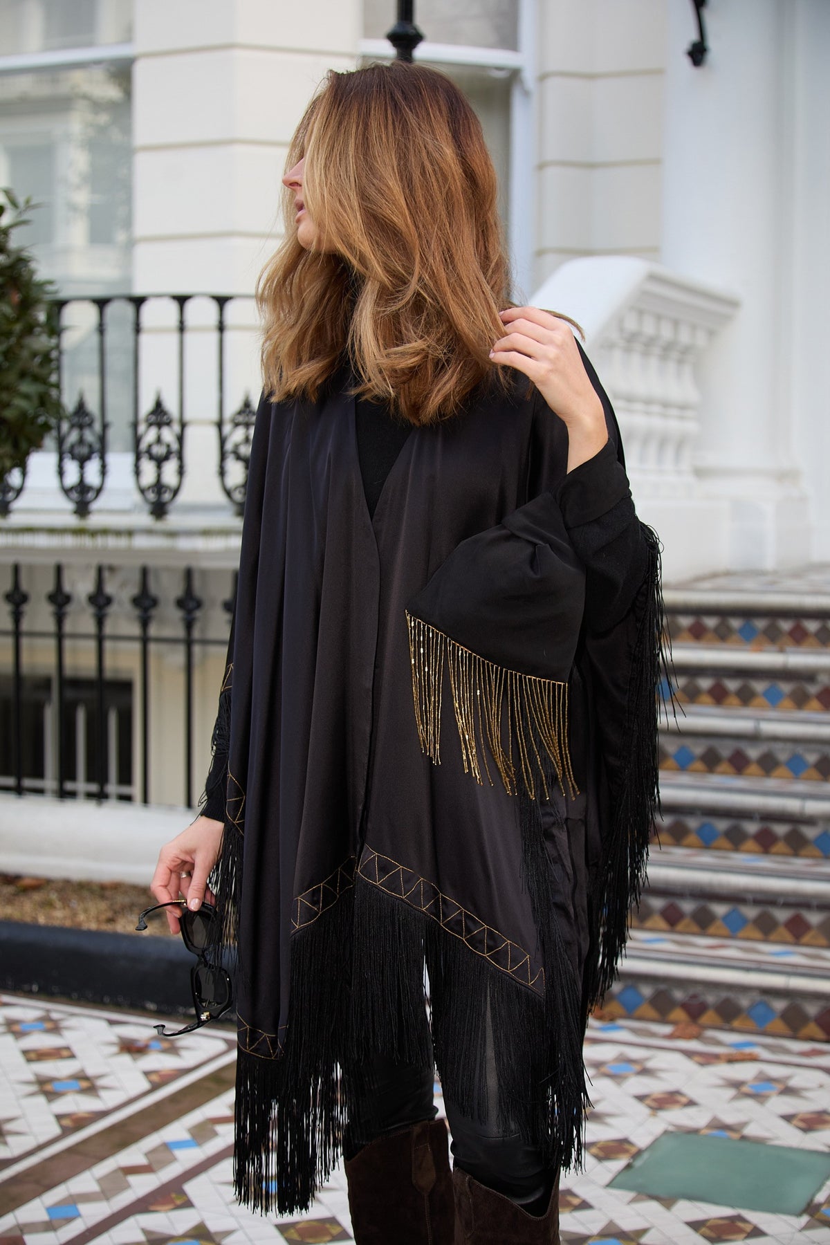 The Nomad Poncho in black silk with gold embroidery, three-quarter view
