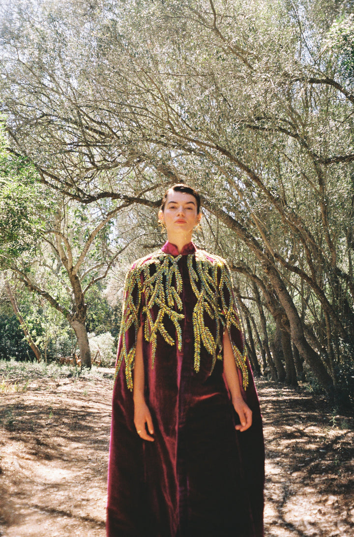 The Royal Garden Cape in magenta silk velvet with gold and green leaf embroidery, front view, olive grove