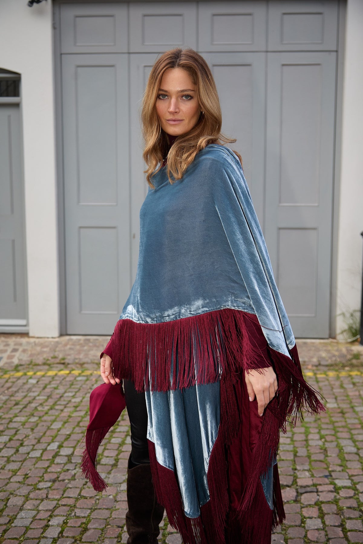 The Summer Cloud Poncho in light blue silk velvet with burgundy fringe, front three-quarter view