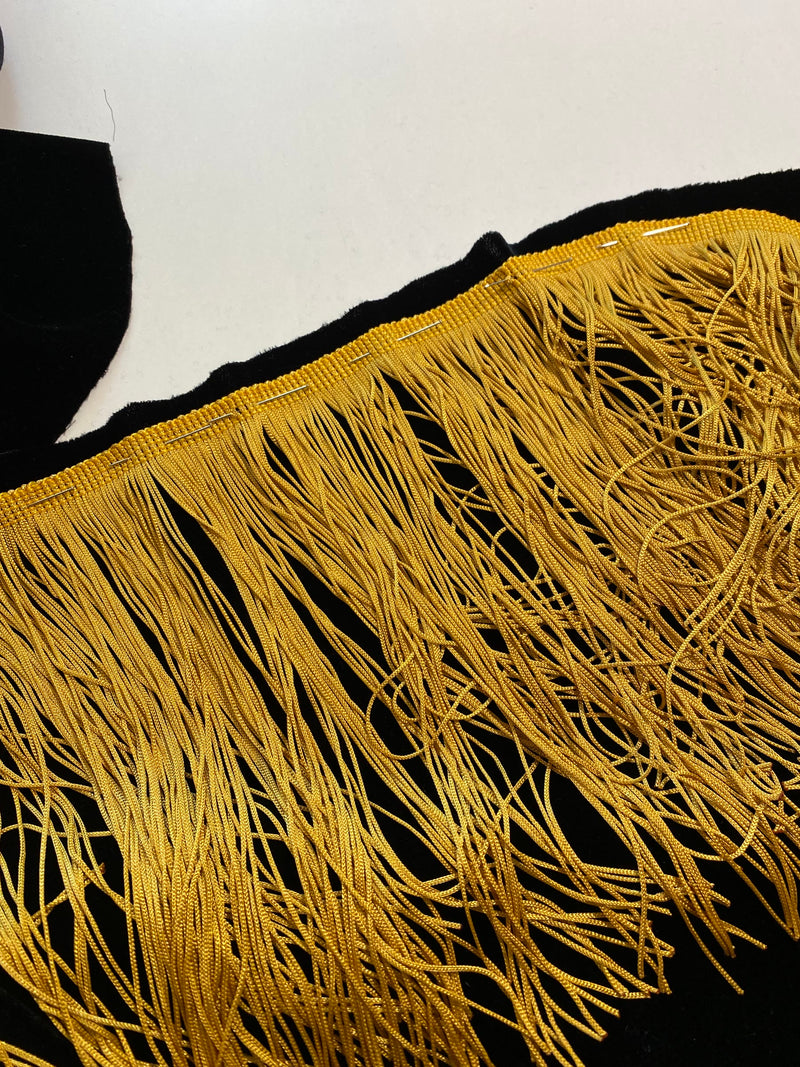 Long gold fringe laid along black silk velvet