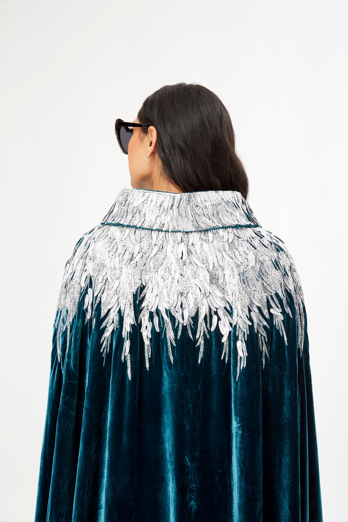 The Silver Feather Cape in petrol silk velvet with silver beaded feathers, feather embroidery, back view, studio