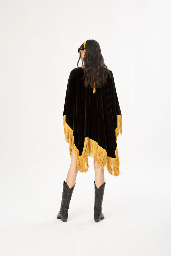 The Golden Age Poncho in black silk velvet with gold fringe, back view, studio