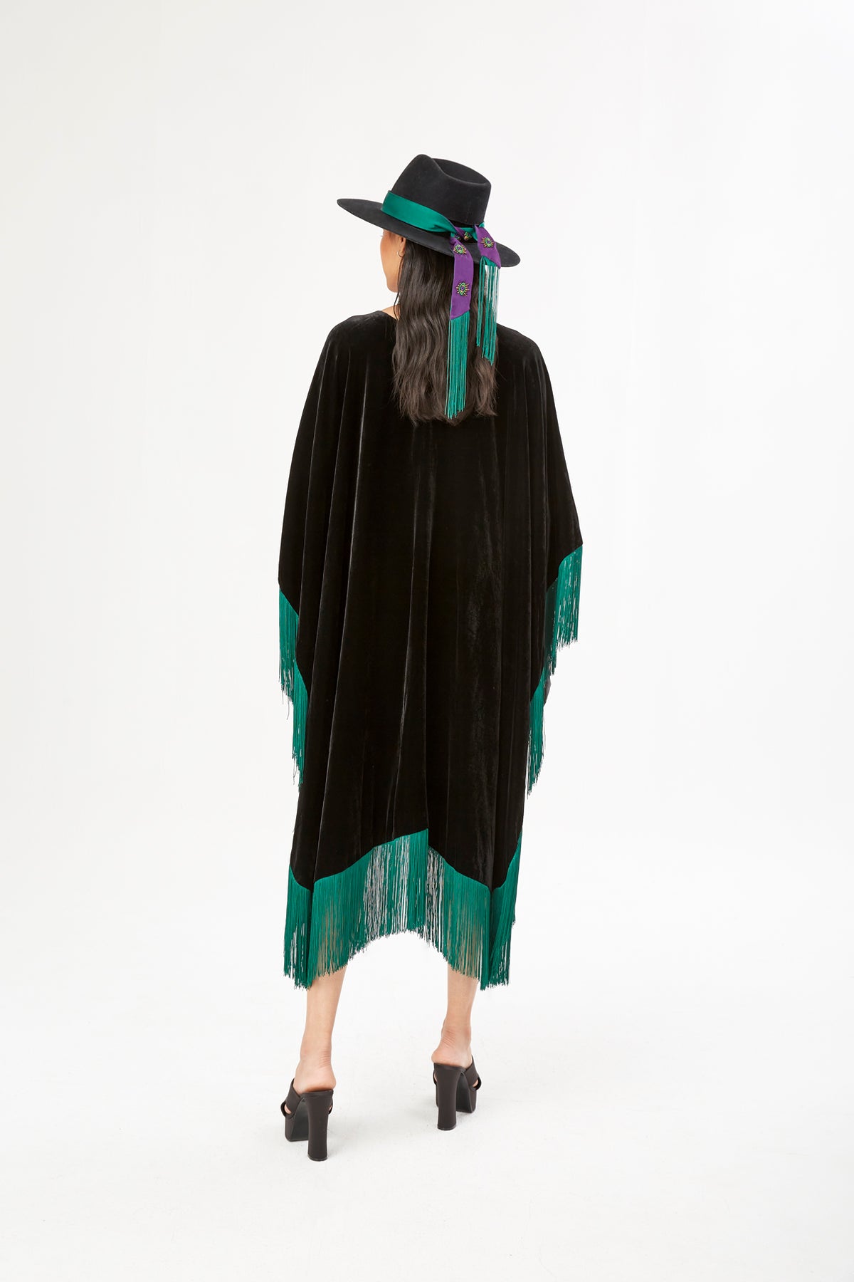 The Gypset Poncho in black silk velvet with emerald fringe, back view, studio