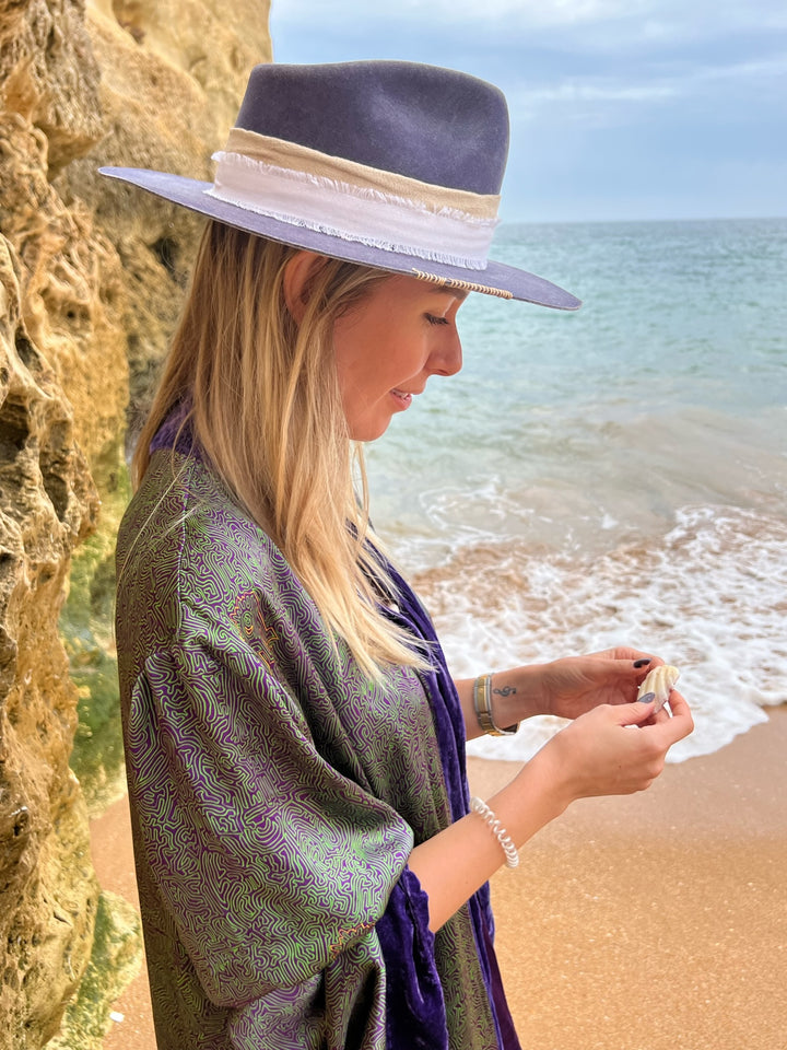 The Mazestroom Kimono, Purple and Green, in iridescent green and purple maze-print silk with velvet trim, side view, beach