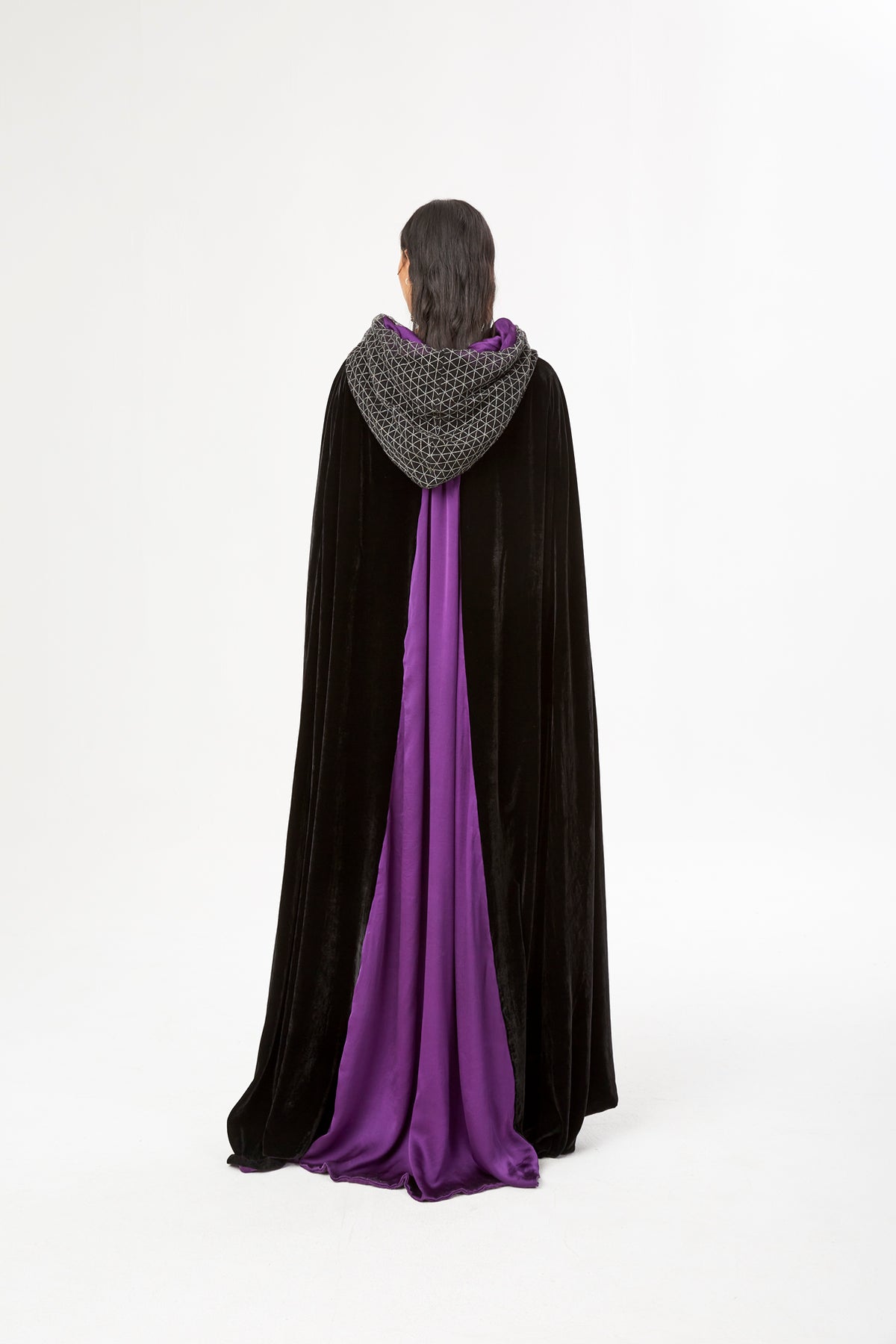 The Mystery Cape in black silk velvet with purple lining and embroidered hood, back view, studio