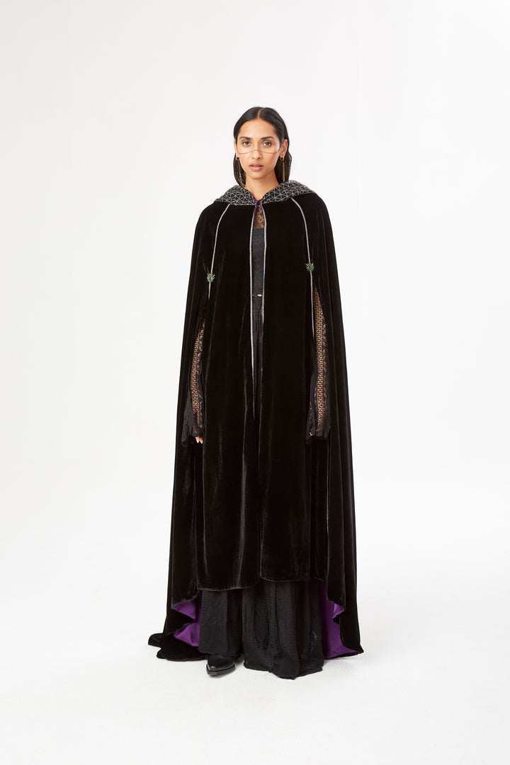 The Mystery Cape in black silk velvet with purple lining and embroidered hood, front view, studio