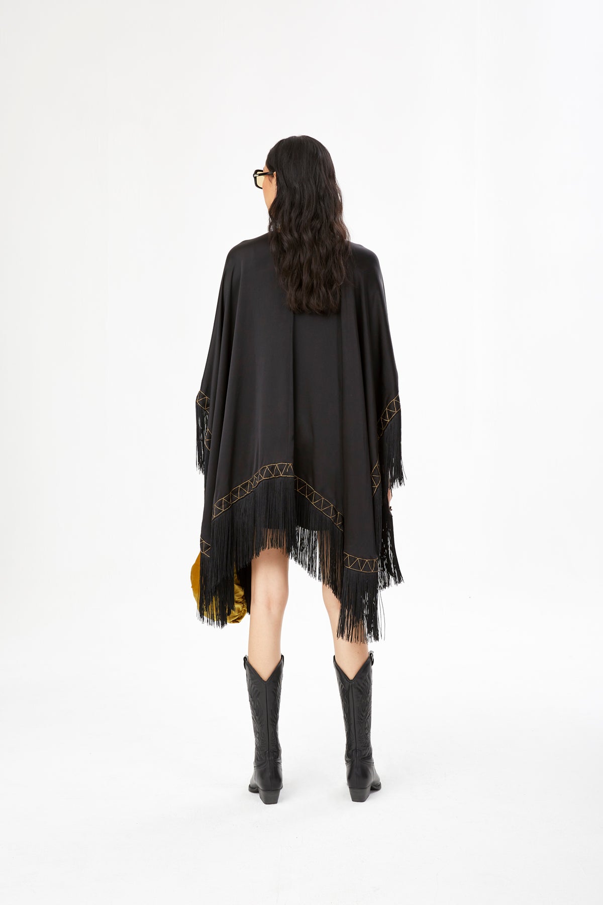 The Nomad Poncho in black silk with gold hand embroidery and black fringe, back view, studio