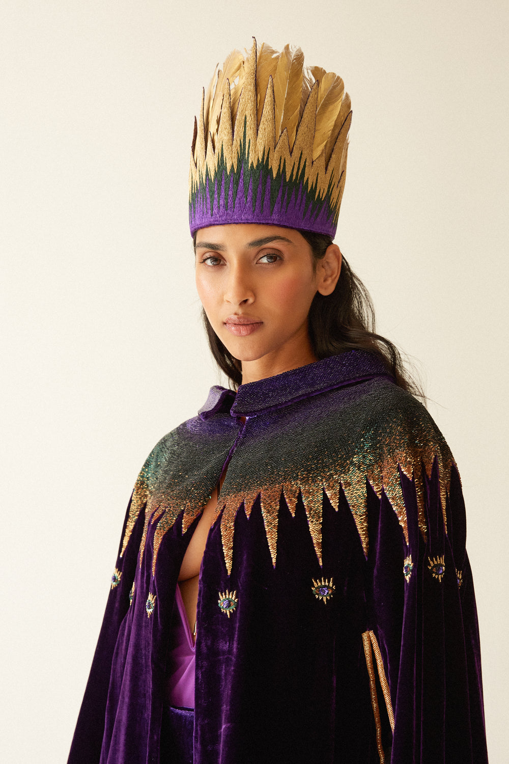 The Rainbow Cape in purple silk velvet with rainbow sequin collar, collar detail with gold headdress, studio