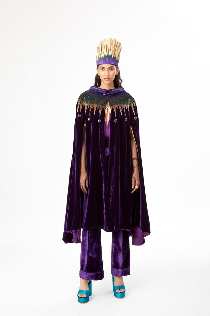 The Rainbow Cape in purple silk velvet with rainbow sequin collar, front view with gold headdress, studio