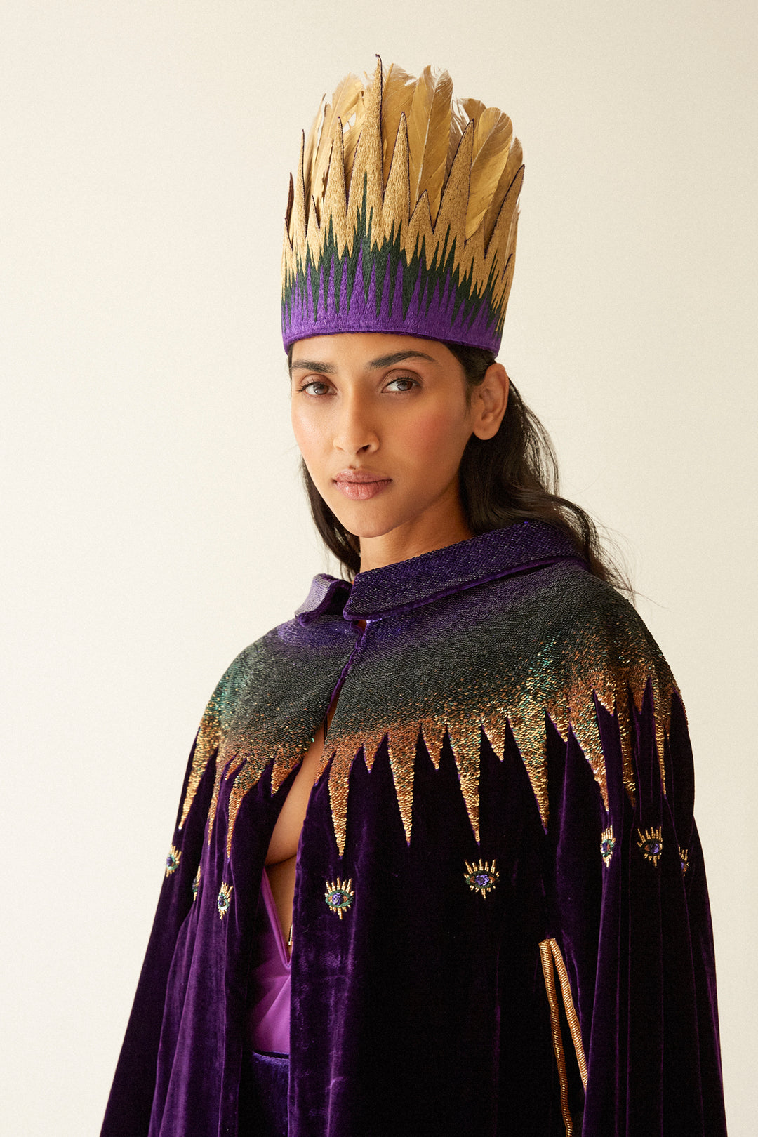 The Rainbow Feather Headdress with golden feathers on a purple band, close-up, studio